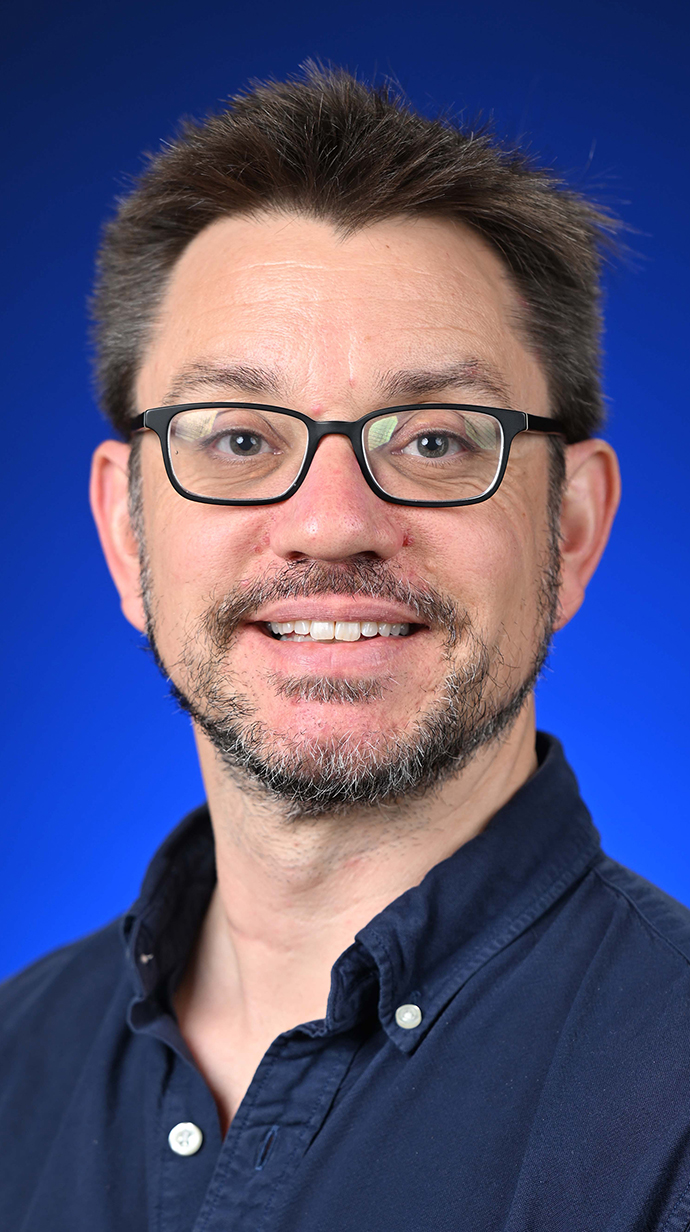 Headshot of a man wearing a dark blue shirt.