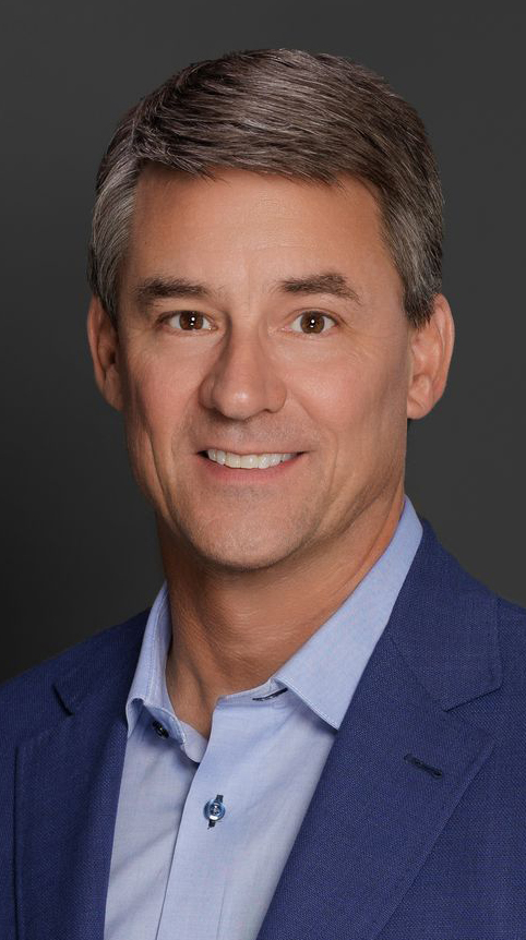 A man wears a blue sport coat over a light blue shirt.