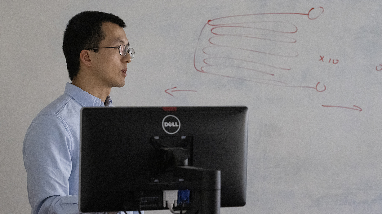 A man stands in front of a whiteboard lined with equations.
