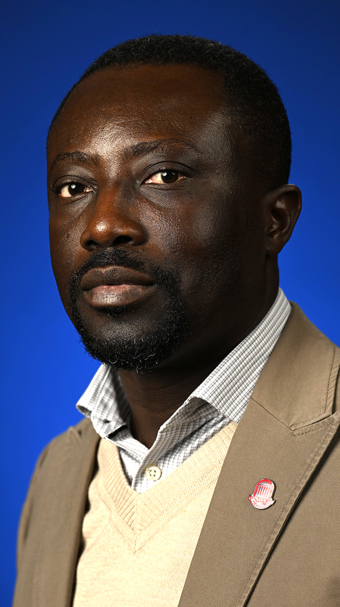Headshot of a man wearing a tan sport coat over a beige sweater.