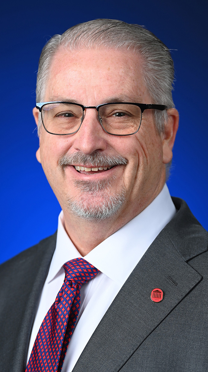 Headshot of a man wearing a gray suit.