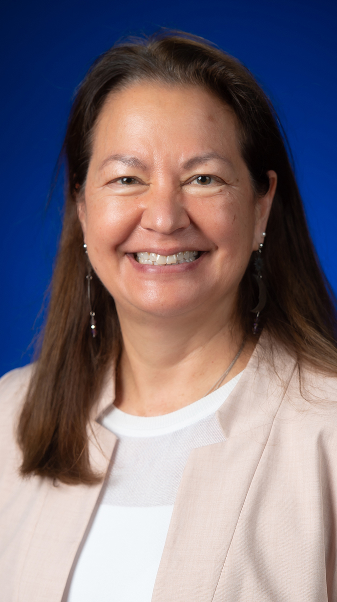 Headshot of a woman wearing a beige jacket over a white blouse.