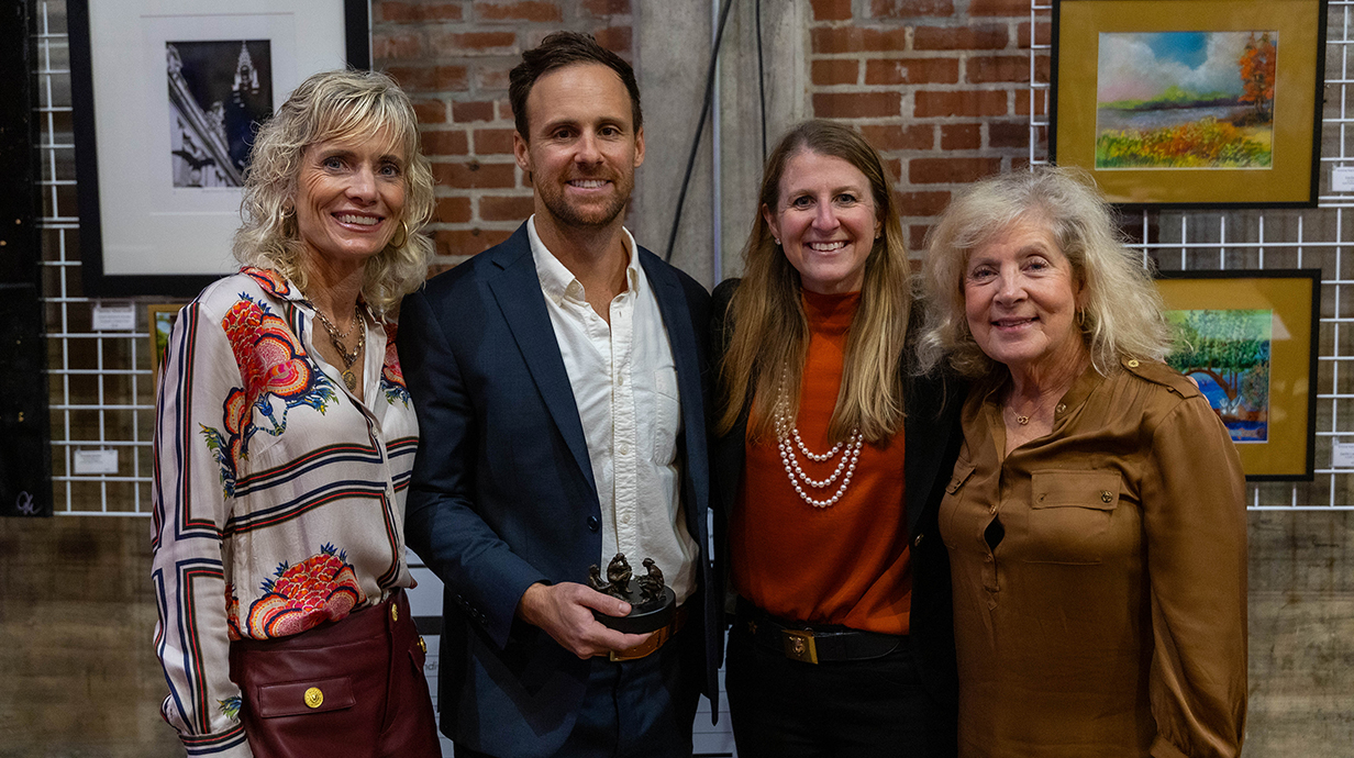 A young man stands with three women.