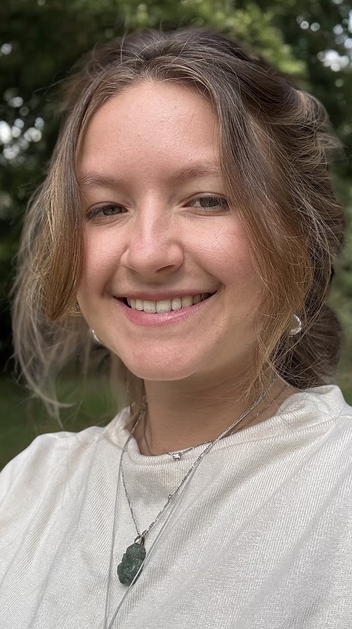 A young woman wears a white sweater.