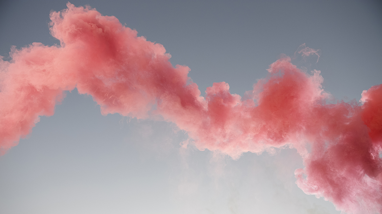 A column of pink smoke blows through the frame.