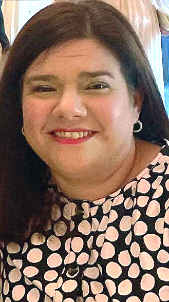 Headshot of a woman wearing a black top with pink polka dots.