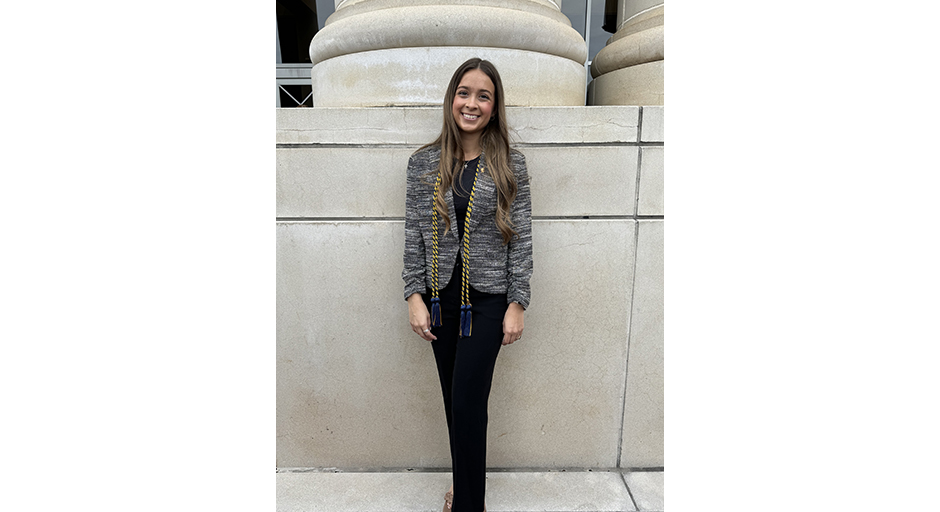 An image of Lauren standing in front of a column at the Ford Center wearing her ropes from the Provost Scholar induction ceremony.