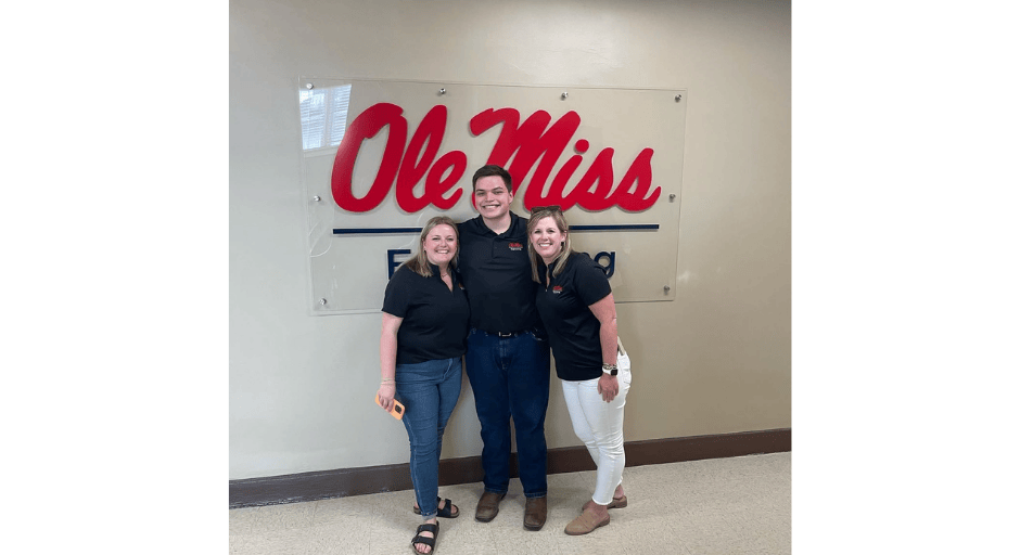Image of Parker Flowers, Byron Swetman and engineering assistant dean Megan Miller posing together in front of a wall with a sign behind them that reads "Ole Miss Engineering".