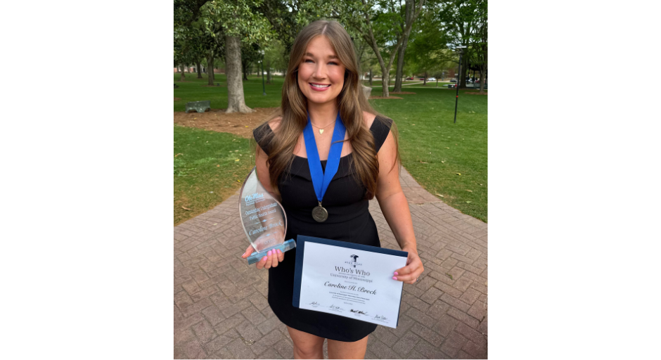 Image of Caroline Brock wearing a medal and holding a certificate and award