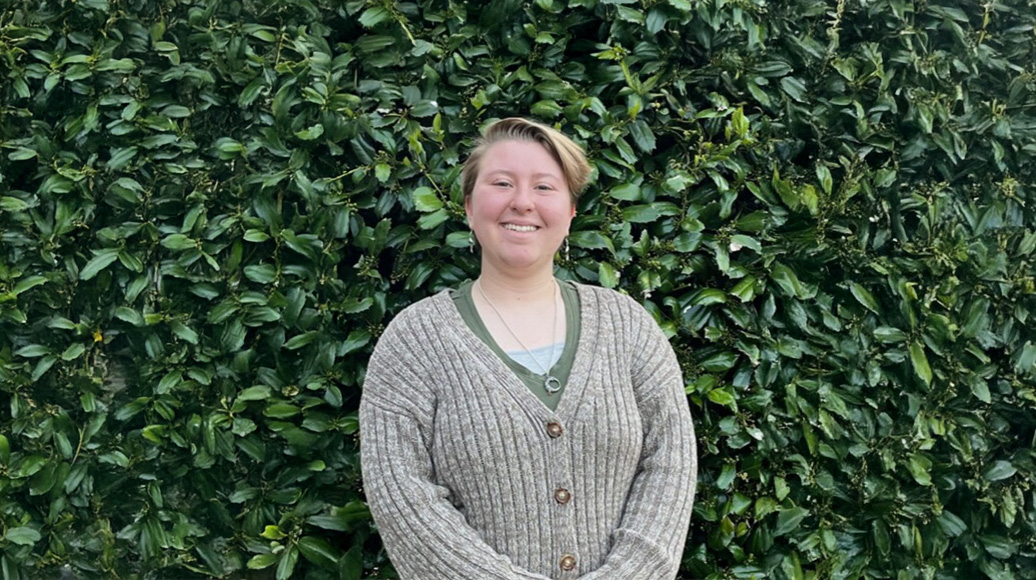 Image of Gwen Pfrenger in front of green foliage.