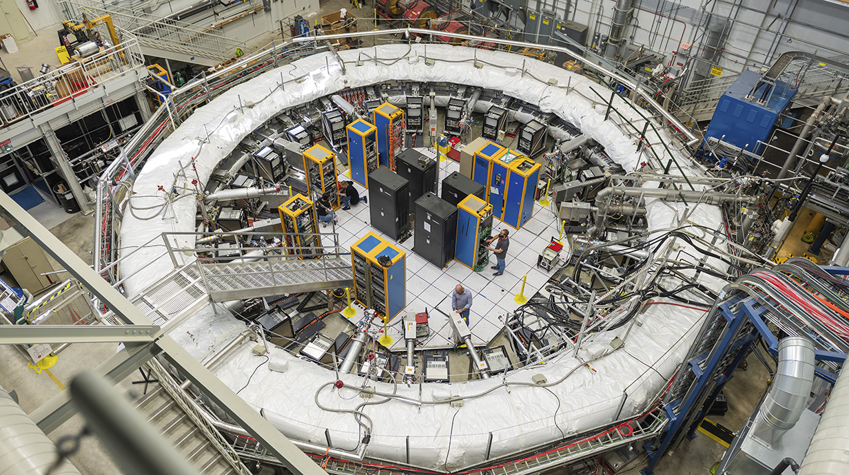 A giant metal ring is surrounded by computers and other high-tech equipment.