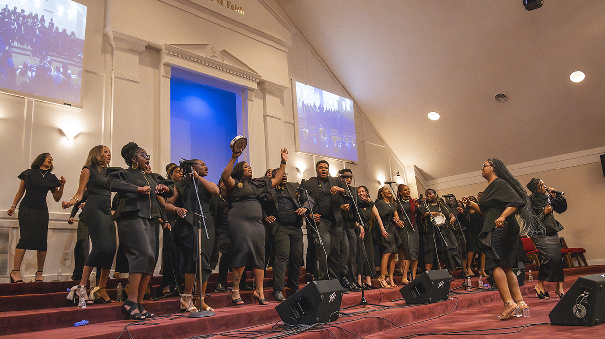 A choir, all dressed in black, performs at the front of a large church.