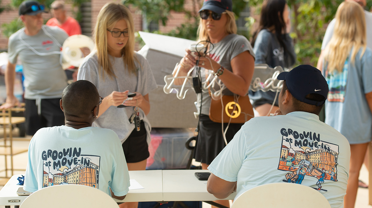 Two young women get advice from two men wearing Move-In T-shirts.
