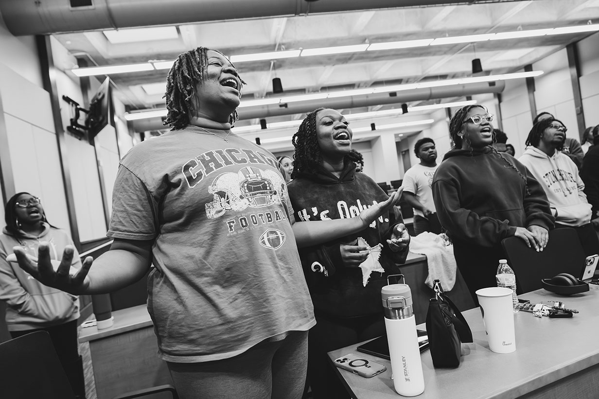Two African American women, sisters Zharia and Zkyra Metcalf, singing together during rehearsal, both wearing casual clothing and appearing engaged in the music.