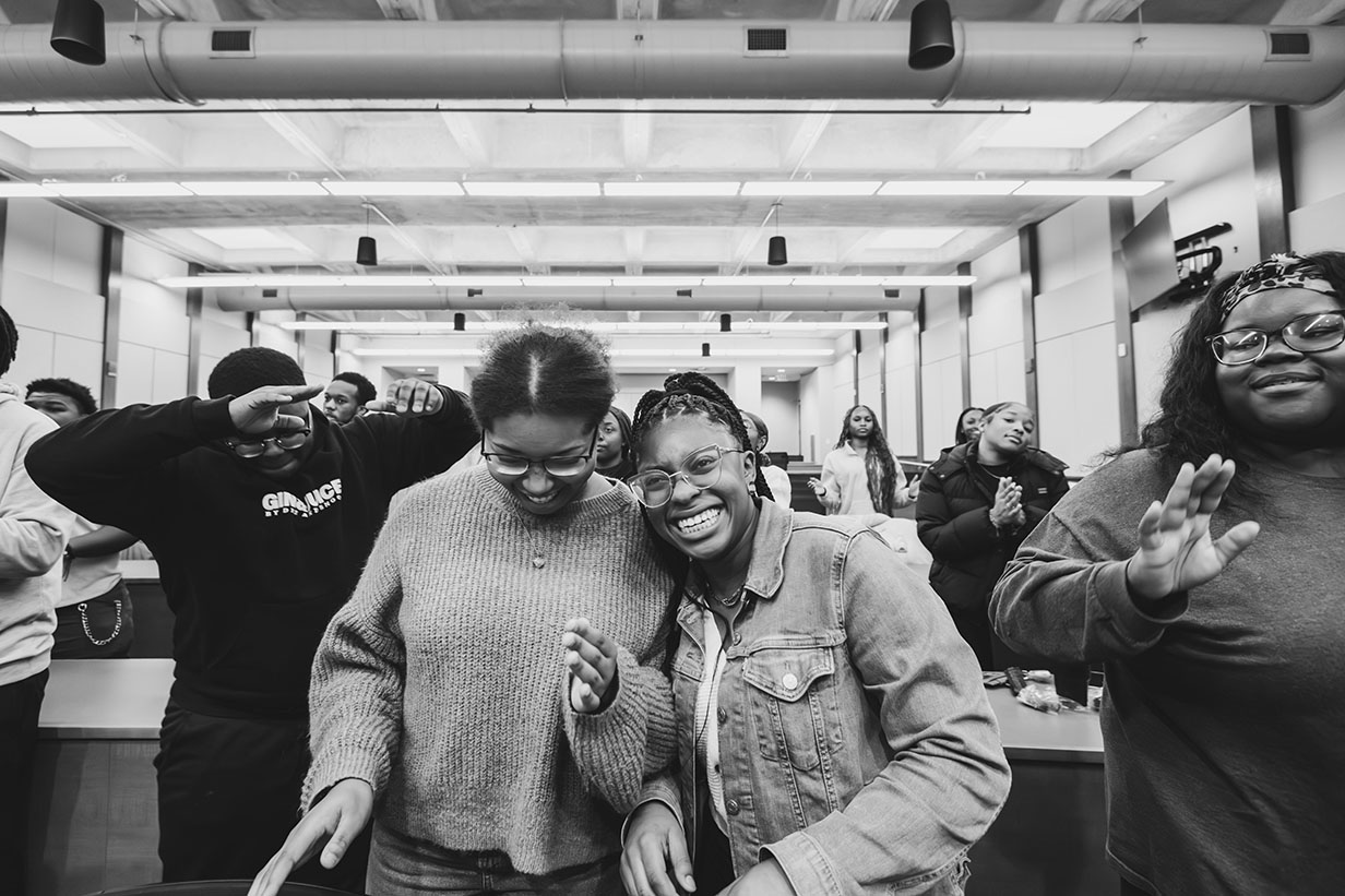 Two choir members, Tanissa Ringo and Ashlee Simone Silliman, laughing together during rehearsal, showing the camaraderie within the group.
