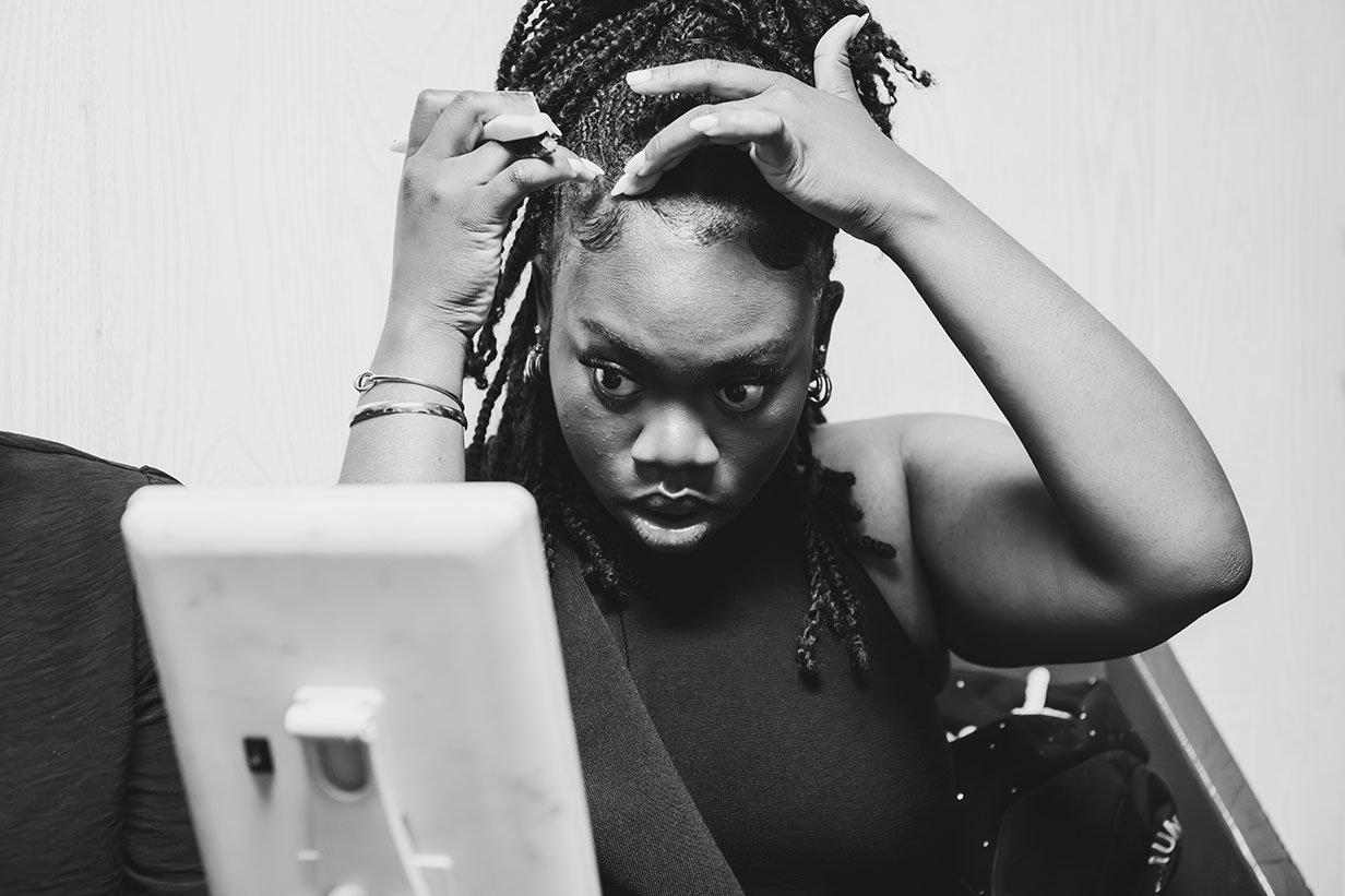 Choir member Zkyra Metcalf adjusting her hair while getting ready for the concert performance, dressed in black concert attire.