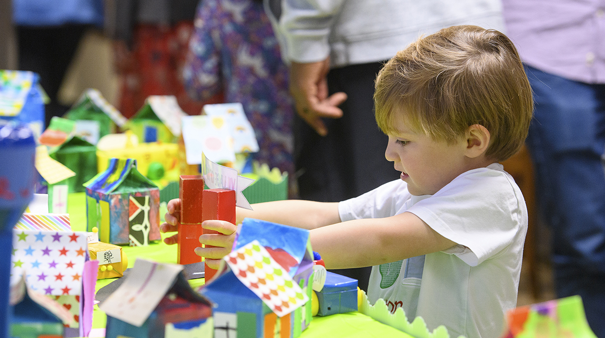 A young boy pays with colorful artwork on a table.