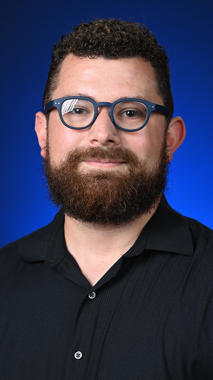 Headshot of a man wearing a black shirt and glasses.