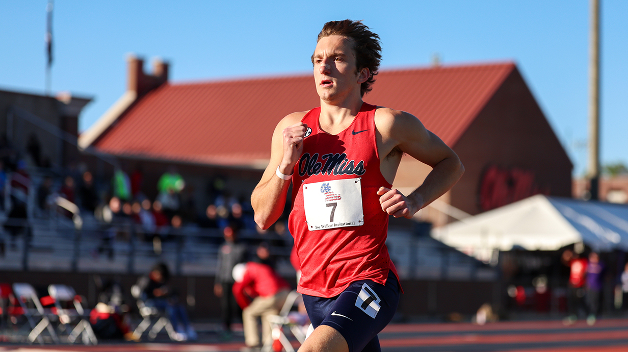 A young man competes in a track running event in a stadium.