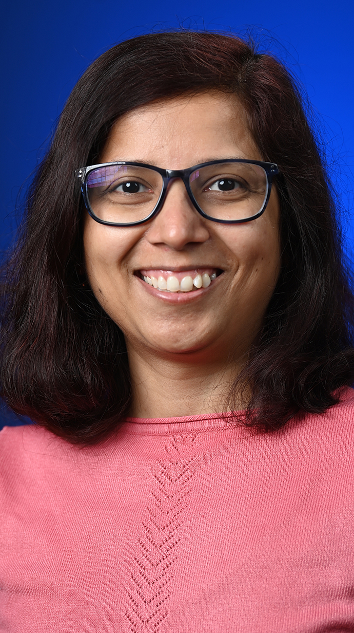 Portrait of a woman wearing a pink sweater and glasses.