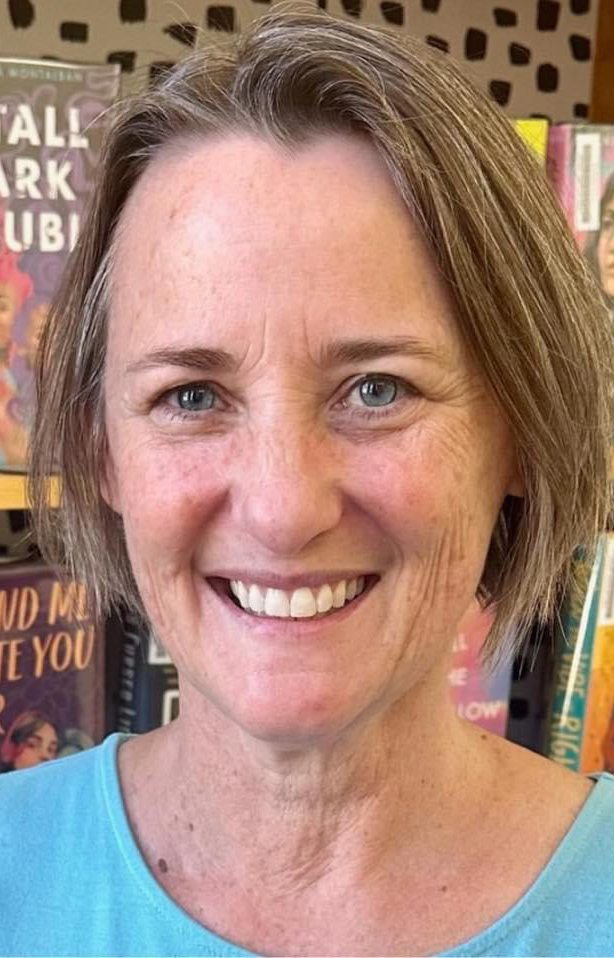 Headshot of a woman standing in front of shelves full of books.