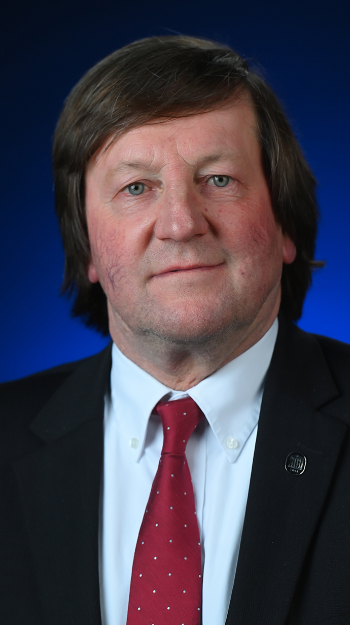 Headshot of a man wearing a blue suit with a red tie.