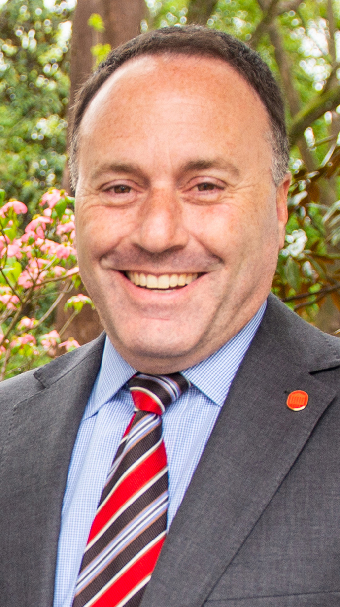 Headshot of a man wearing a gray suit and with a striped tie.
