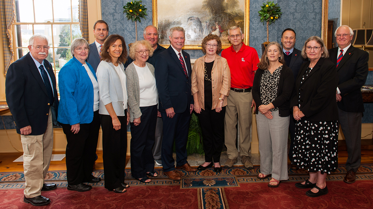 A large group of people lines up for a photo in an ornate parlor.