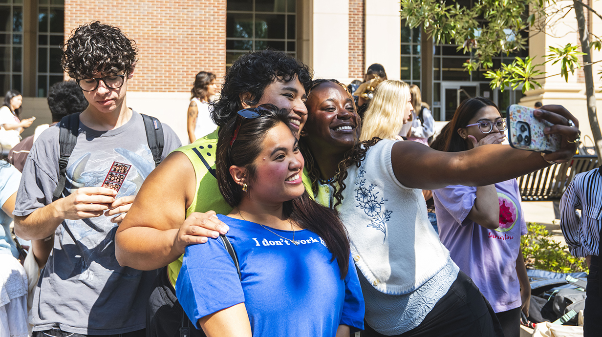 A group of people takes a selfie on an outdoor courtyard.