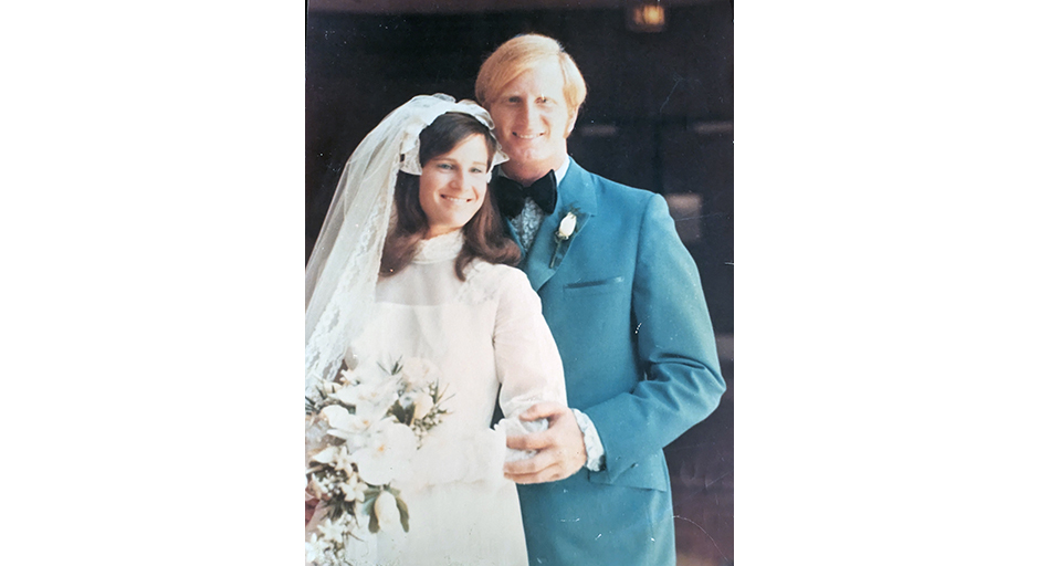 A woman in a wedding dress and a man in a suit pose for a wedding photo.