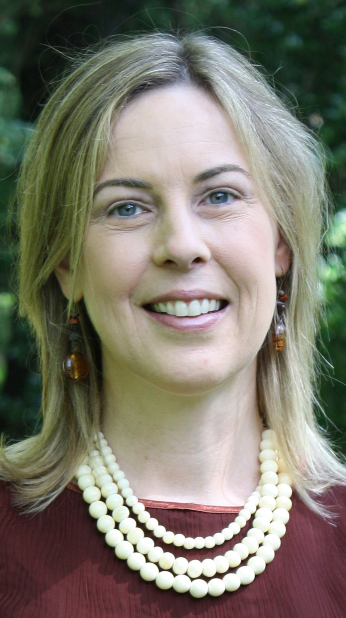 Headshot of a woman wearing a pearl necklace over a red top.