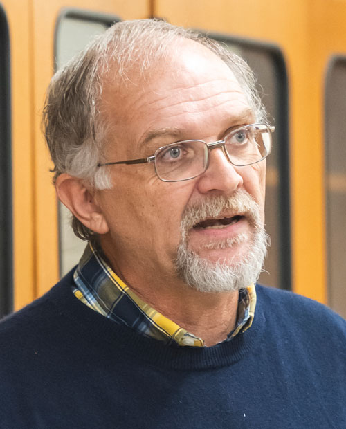 Richard Buchholz is pictured wearing a blue shirt with a yellow and white plaid undershirt.