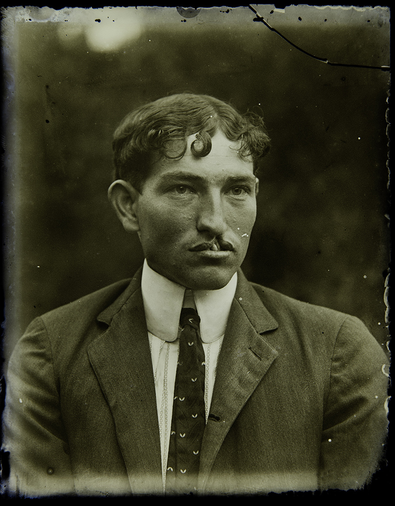 A man poses for a vintage sepia-toned glass plate photograph.