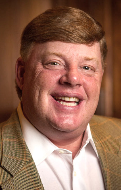 Headshot of a man wearing a brown coat.