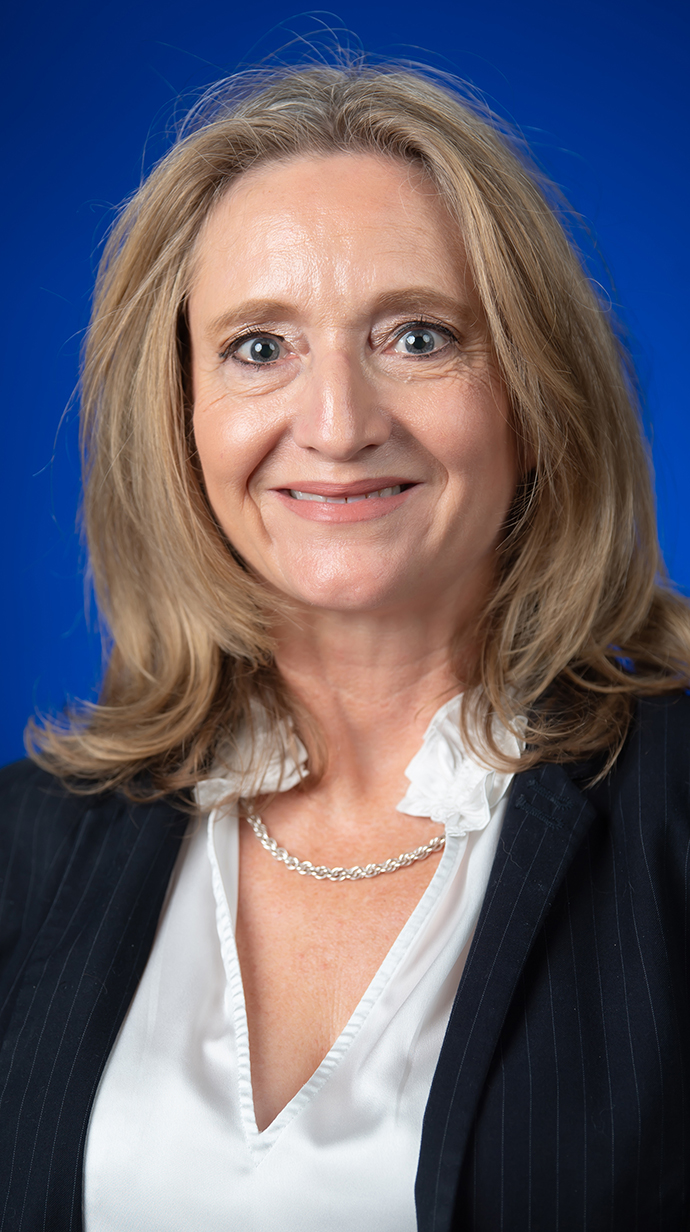 Headshot of a woman wearing a black jacket over a white blouse.