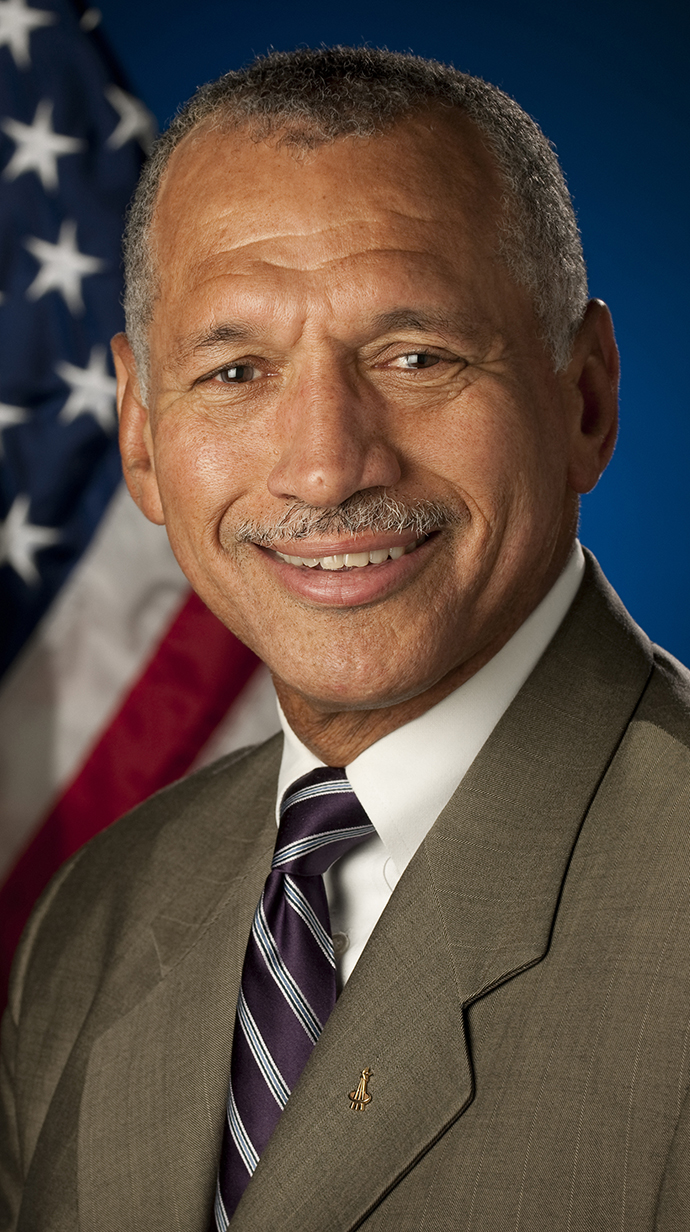 Headshot of a man standing in front of an American flag.