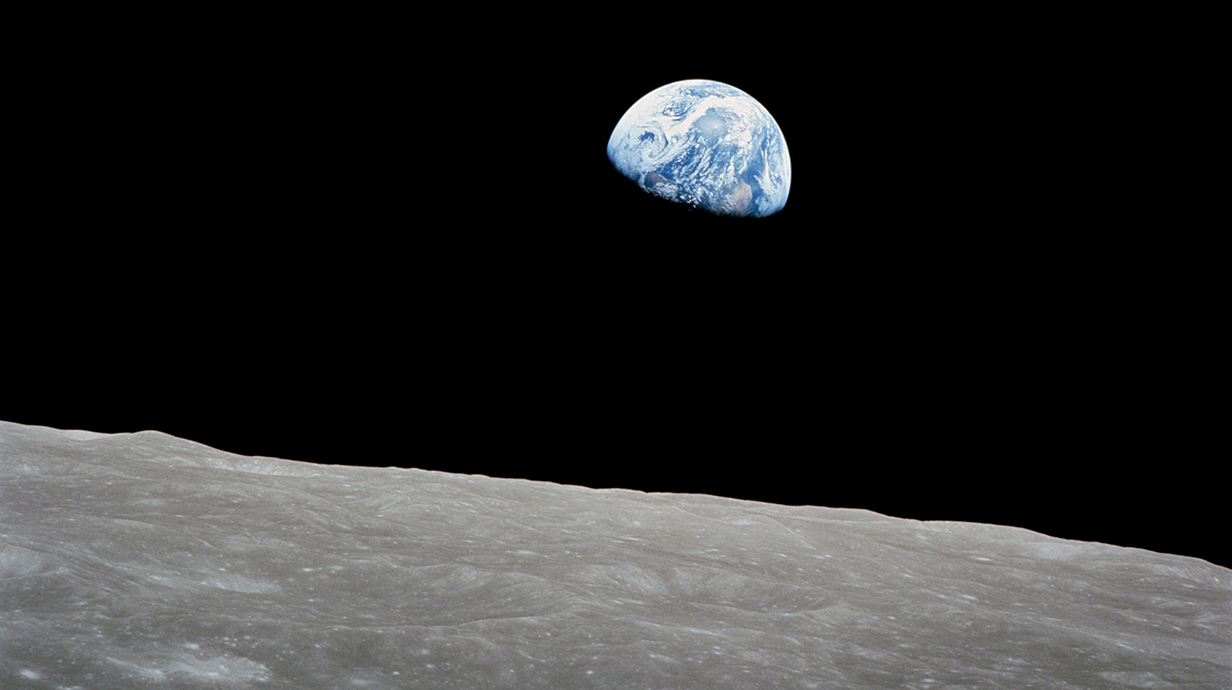 The Earth rises over the surface of the moon.