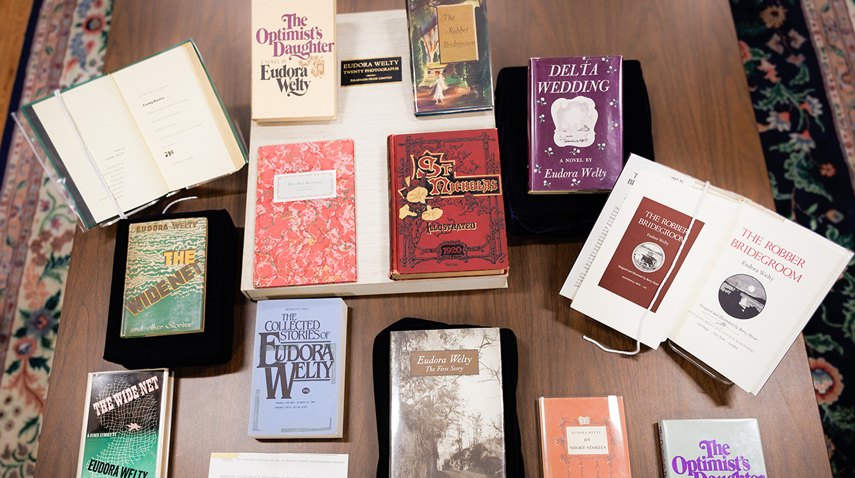 A collection of books is displayed on a wooden table.