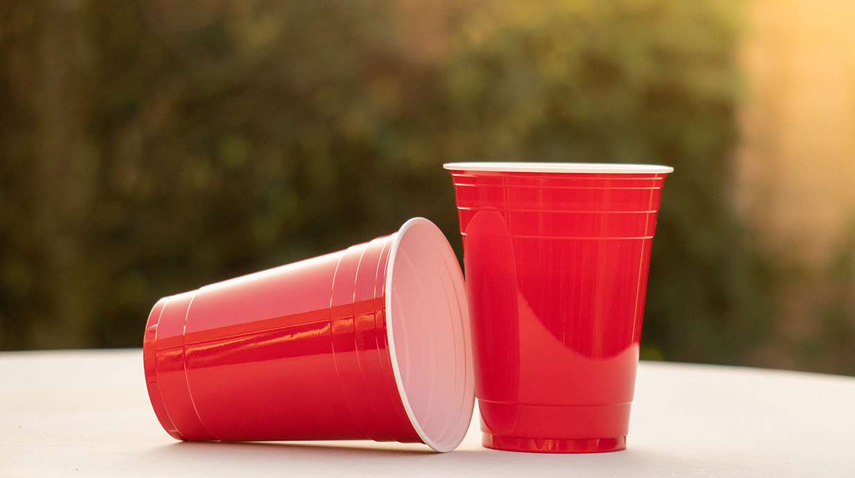 Two red plastic beverage cups sit on an outdoor table.