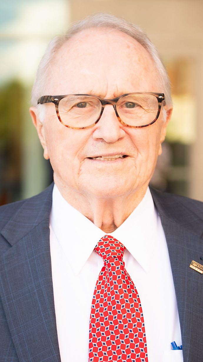 Headshot of a man wearing a dark suit and a red tie.