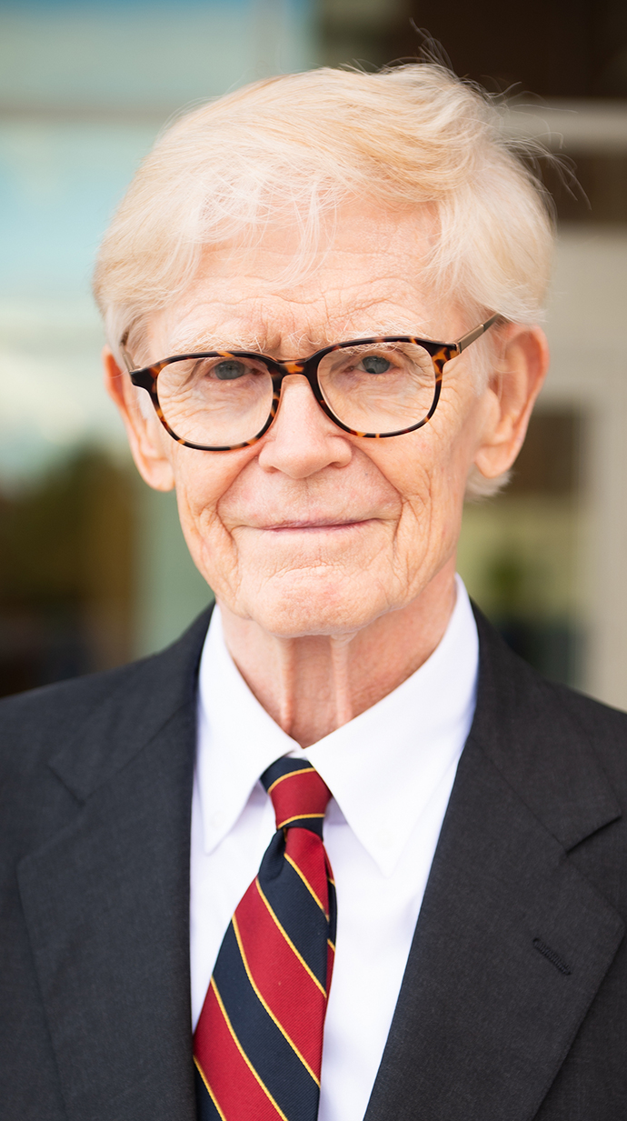 Headshot of an older man wearing a dark suit.