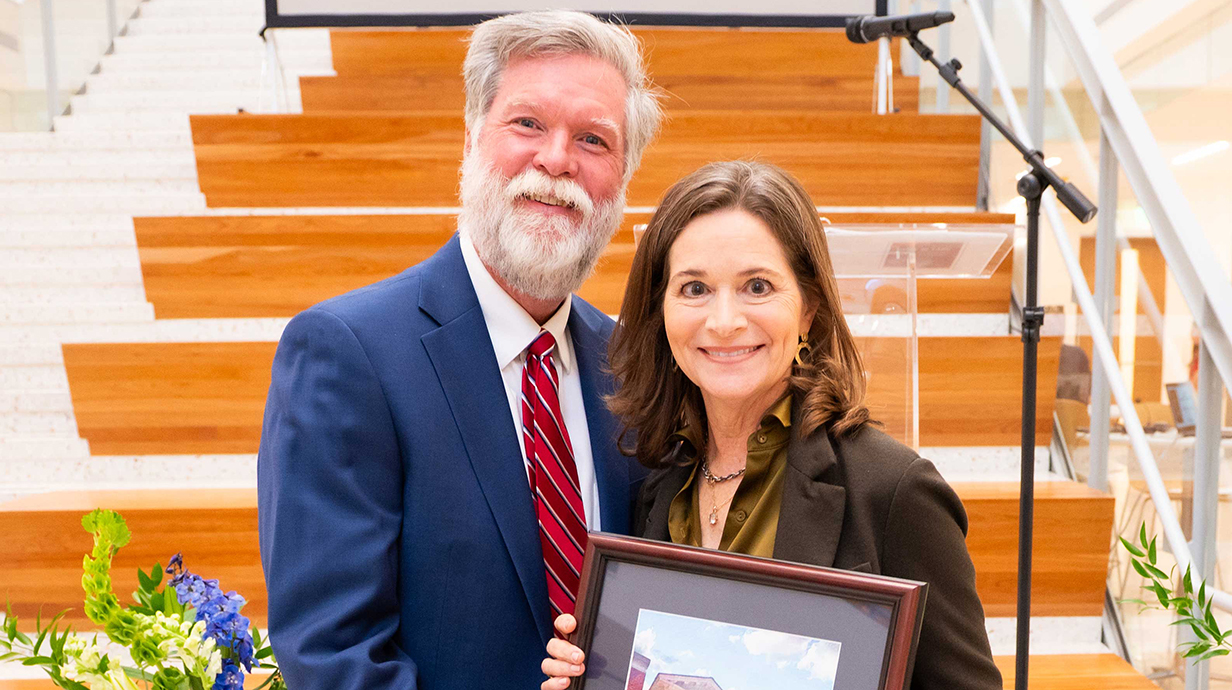 A man presents a woman with an award plaque.
