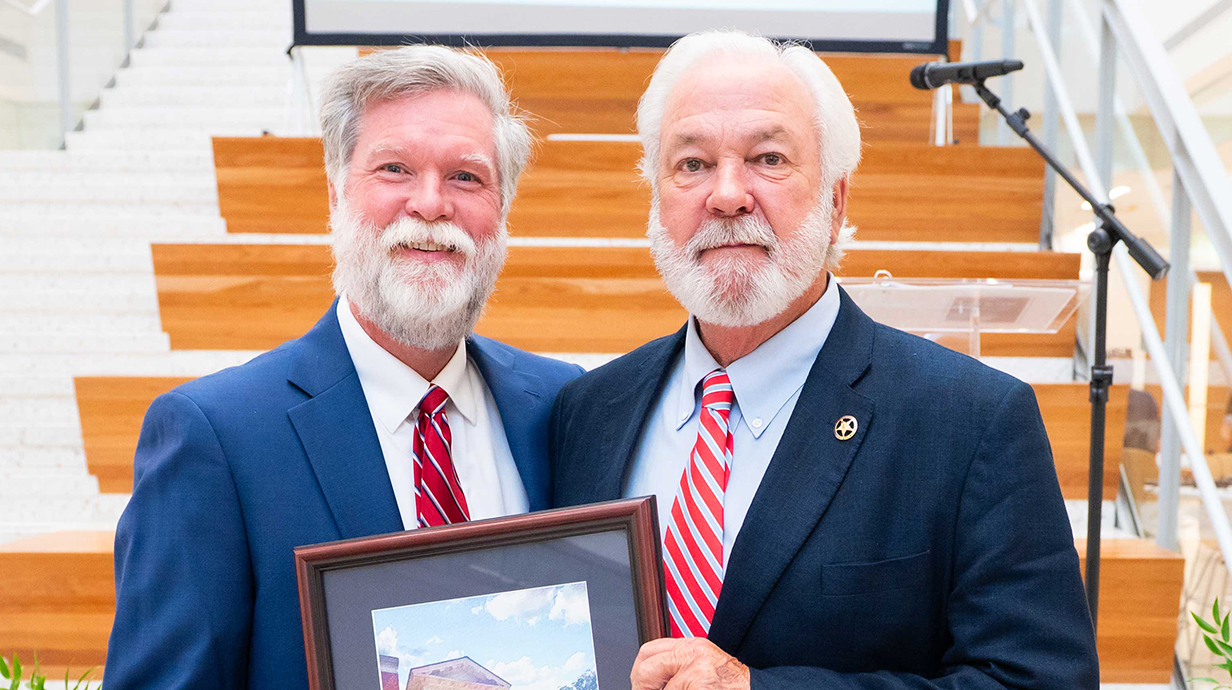 A man presents another man with an award plaque.
