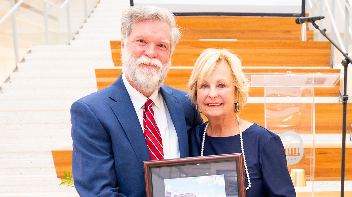 A man presents a woman with an award plaque.