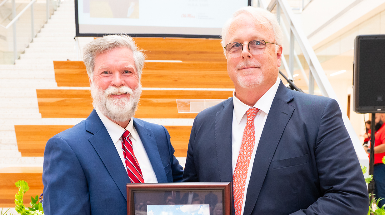 A man presents another man with an award plaque.