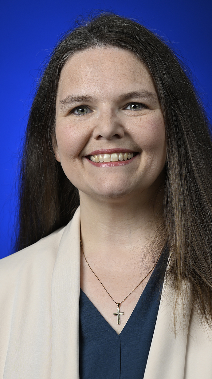 Headshot of a woman wearing a cream jacket over a dark blouse.