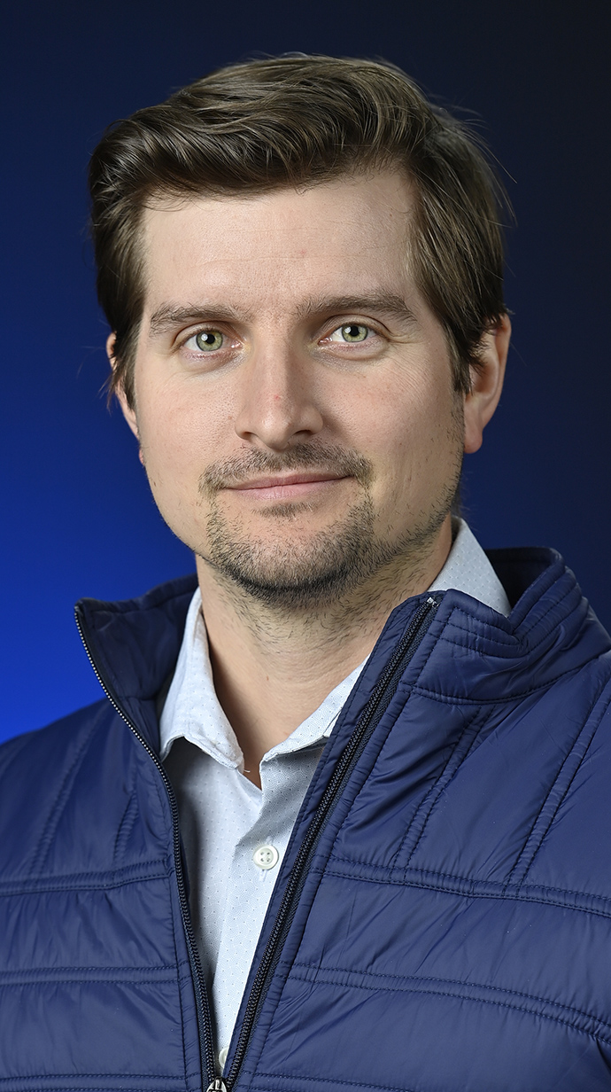 Headshot of a man wearing a blue puffy vest.