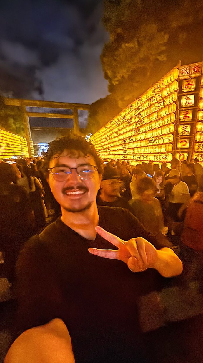 A young man takes a selfie at a nighttime outdoor festival.