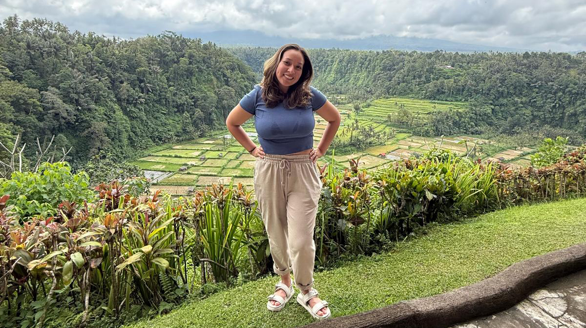 A young woman stands in front of a terraced agricultural field.