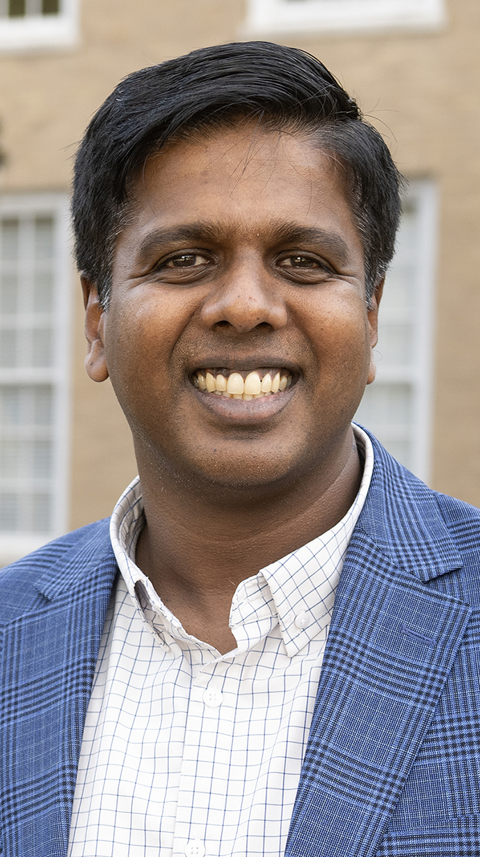 Headshot of a man standing outdoors wearing a light blue sportcoat.